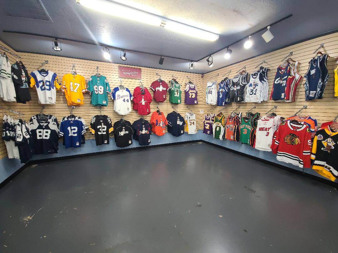 Display of various sports jerseys on a wall in a store.